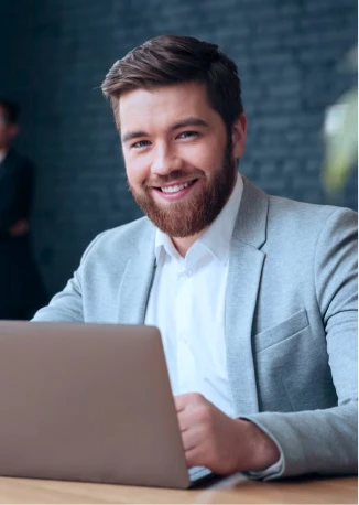 Homem sentado no computador, sorrindo olhando para foto