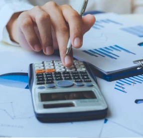 Pessoa trabalhando na calculadora, junto a documentos da empresa.